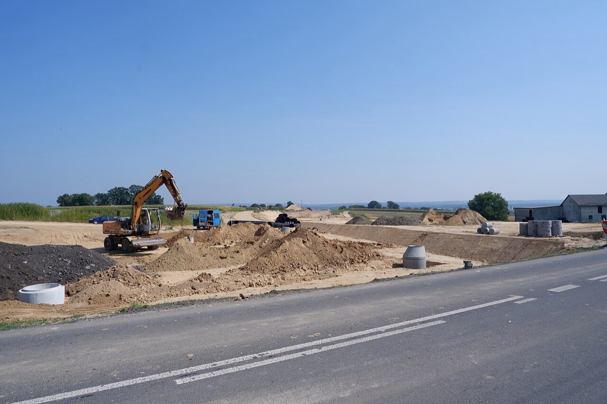 Plac budowy drogi regionalnej z koparką.